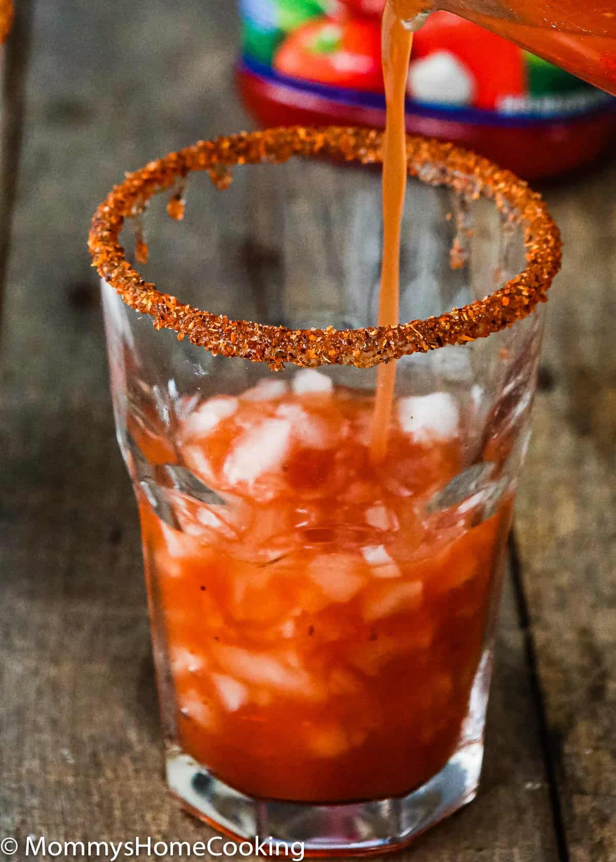 A glass with salted rim with Pineapple Michelada poured into it.