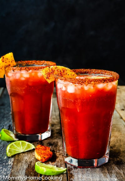 two pineapple micheladas over a wooden board with lime wedges