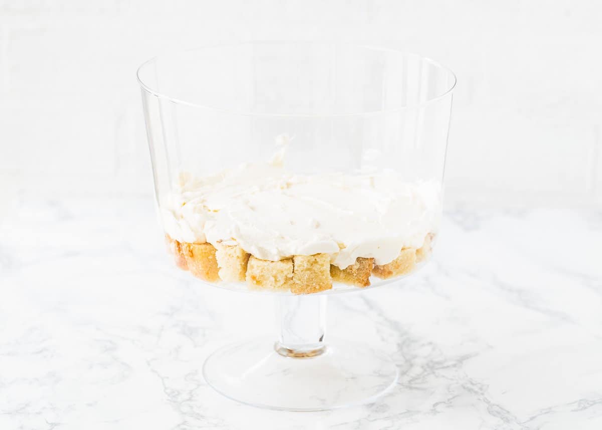 cubed egg-free pound cake on the bottom of a trifle dish topped with whipped cream.