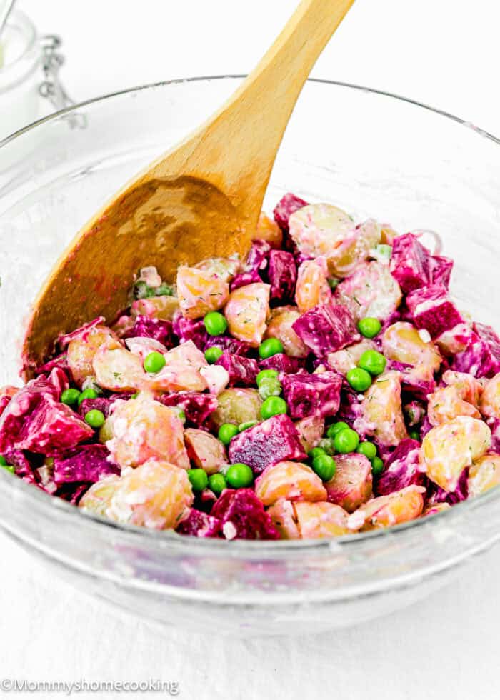Venezuelan Potato and Beet Salad in a bowl with a wooden spoon.