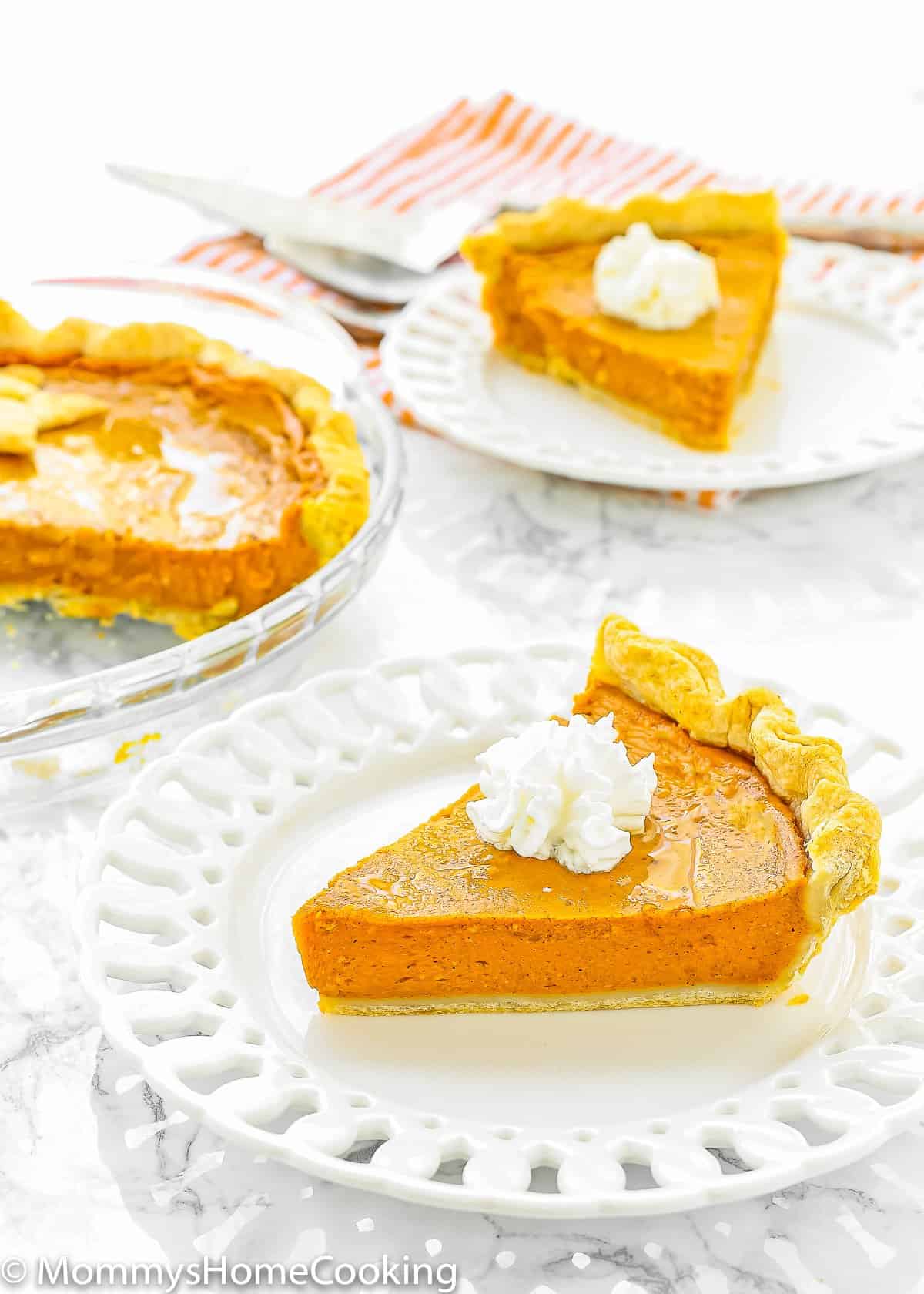 two Eggless Pumpkin Pie slices on white plates over a marble surface.