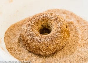 Eggless Apple Cider Donuts being coated with cinnamon sugar