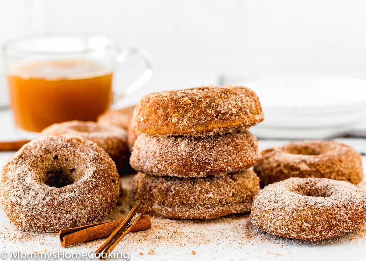 stack of Eggless Apple Cider Donuts with a glass of apple cider in the background