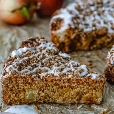 Eggless Apple Maple Spice Cake slice over a parchment paper with red apples in the background