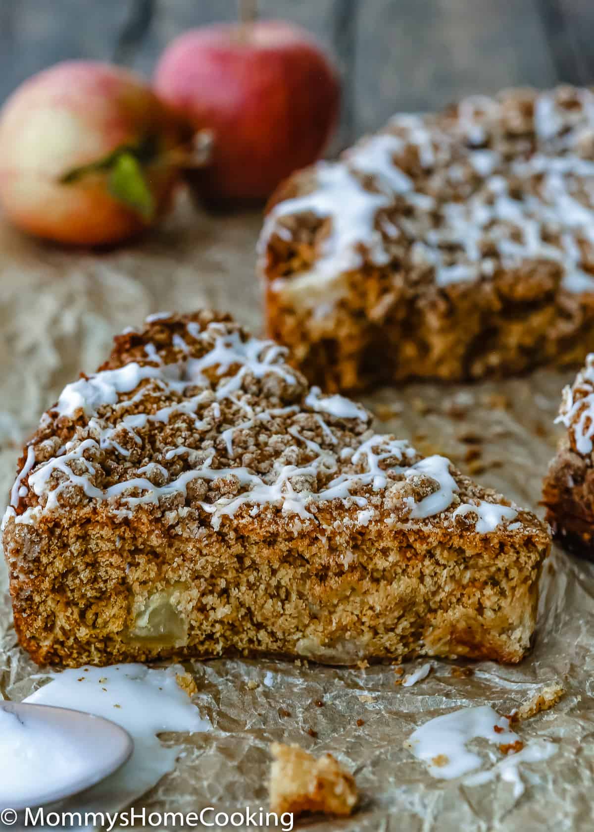 Eggless Apple Maple Spice Cake slice over a parchment paper with red apples in the background.