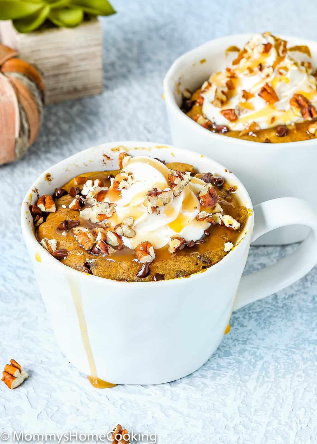 Eggless Chocolate Chip Pumpkin Bread in a Mug with whipped frosting and chopped nuts