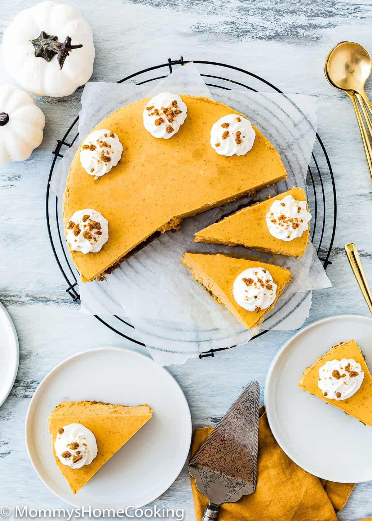 overhead view of a sliced Eggless Pumpkin Cheesecake over a cooling rack. spoons on the side.