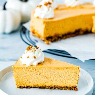 slice of perfect slide of eggless pumpkin cheesecake on a plate decorated with whipped cream