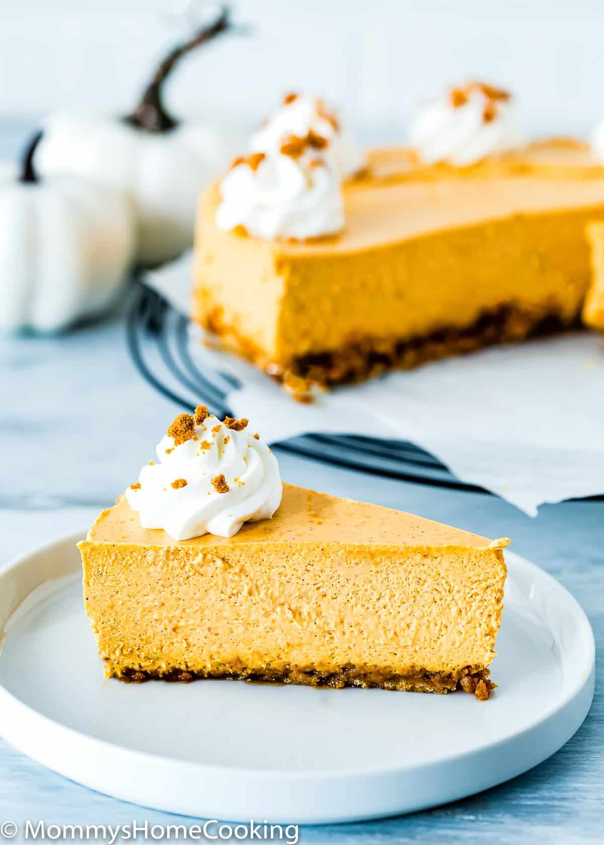 Eggless Pumpkin Cheesecake slice on a plate with whipped cream.