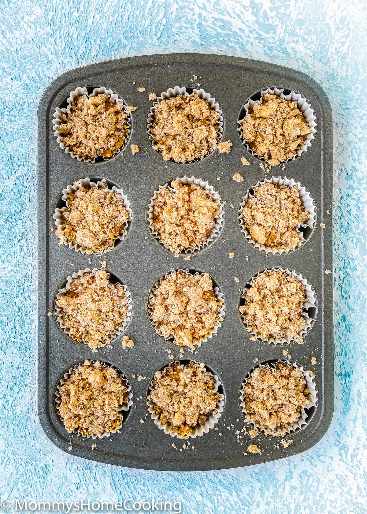 Unbaked Eggless Pumpkin Crumb Muffins in a baking muffin pan.