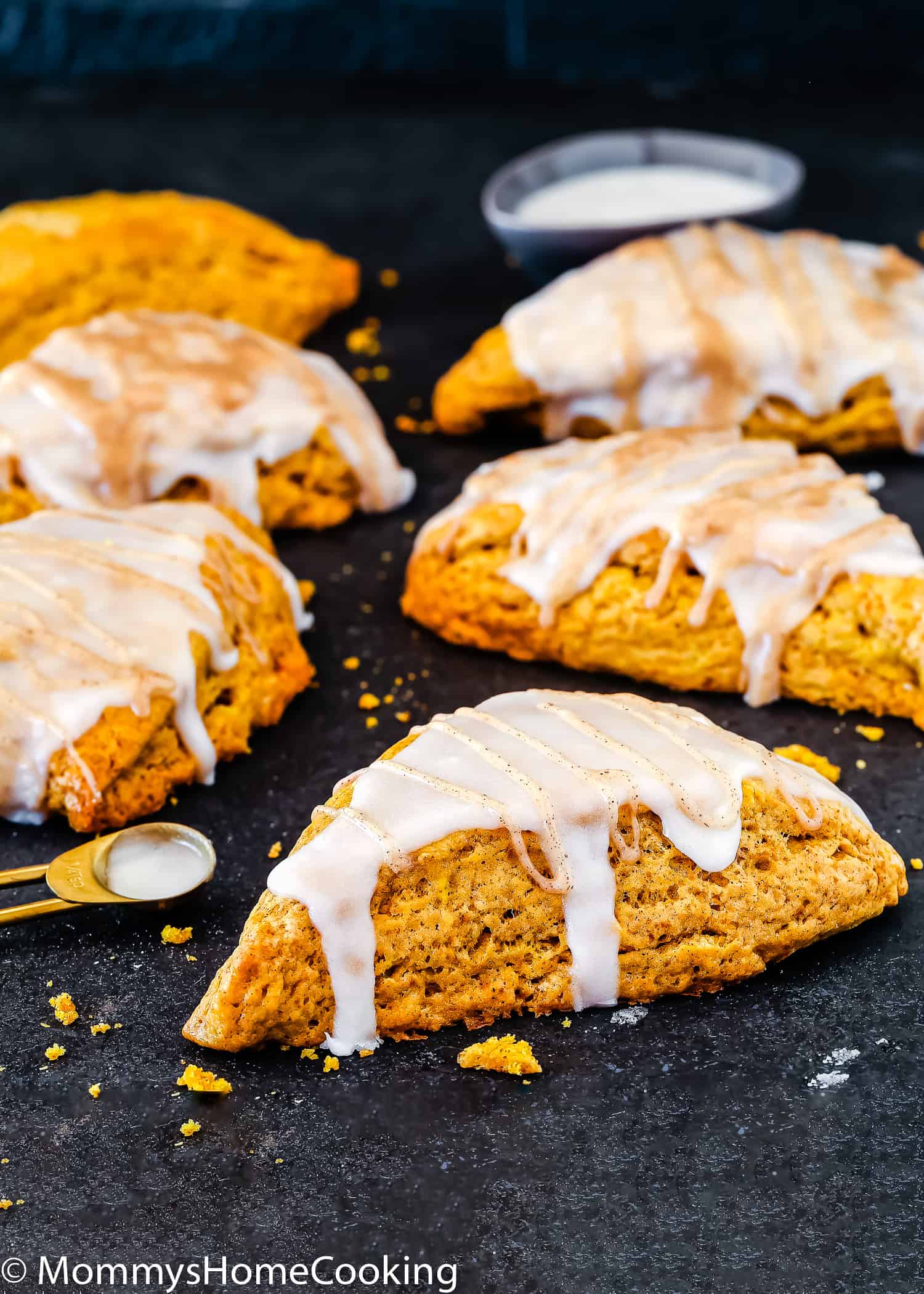 egg-free pumpkin scones with glaze over a black surface.