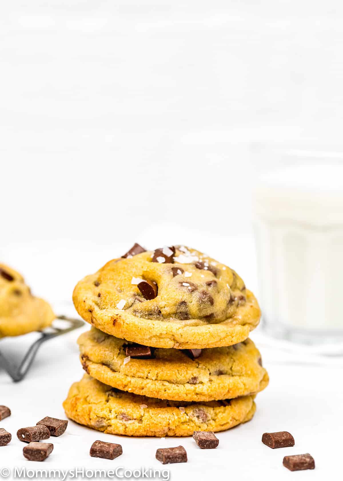 Eggless Chocolate Chip Cookies stack with a glass of milk in the background.