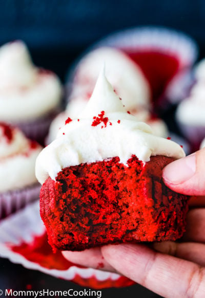 hand holding a bitten egg-free red velvet cupcake showing its fluffy inside texture
