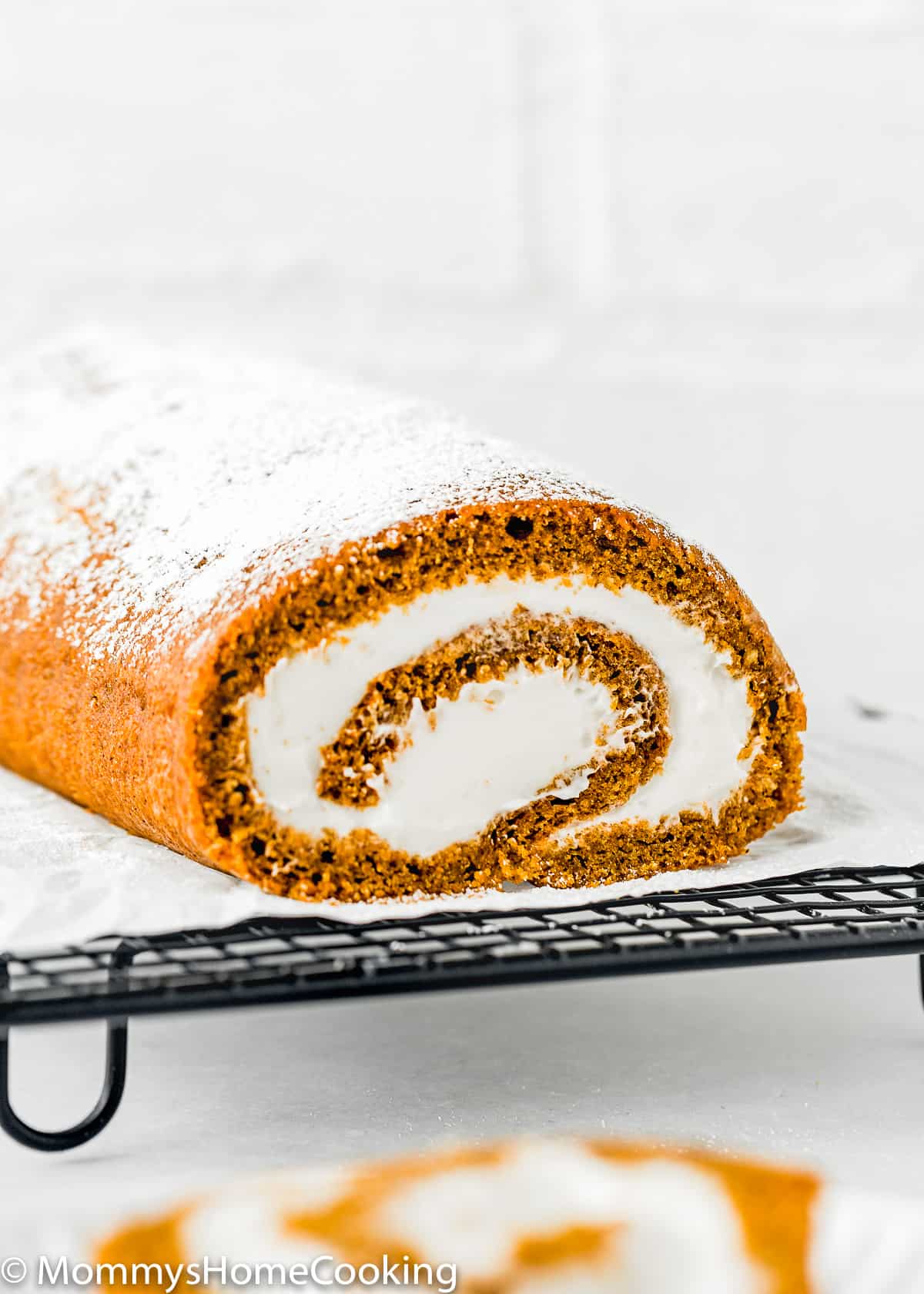 Egg-free Pumpkin Roll filled with cream cheese frosting over a cooling rack.