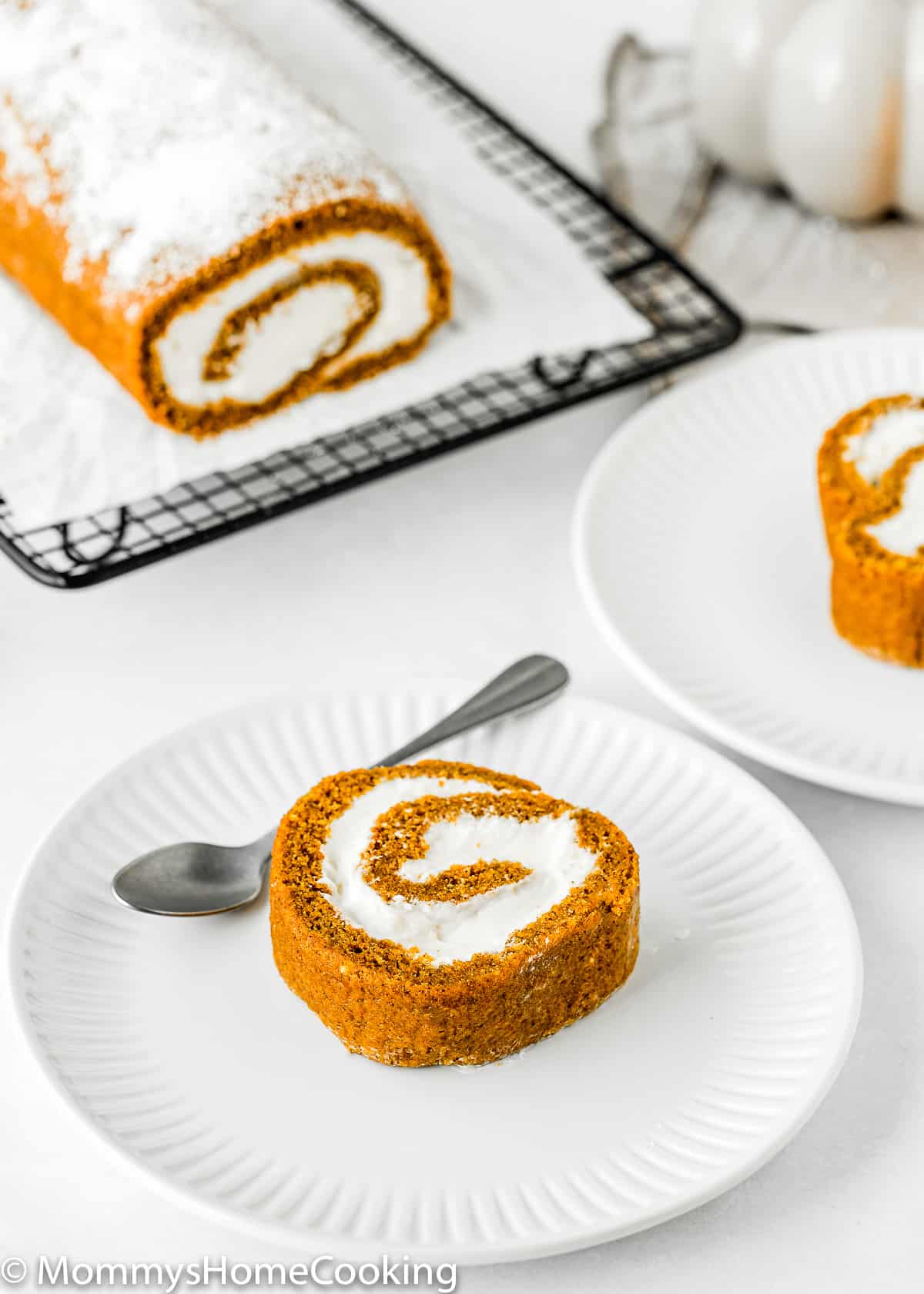 Eggless Pumpkin Roll slice with the whole pumpkin roll in the background.
