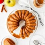 overhead view of a sliced Eggless Apple Cider Donut Cake with brown sugar glaze with apples on the side