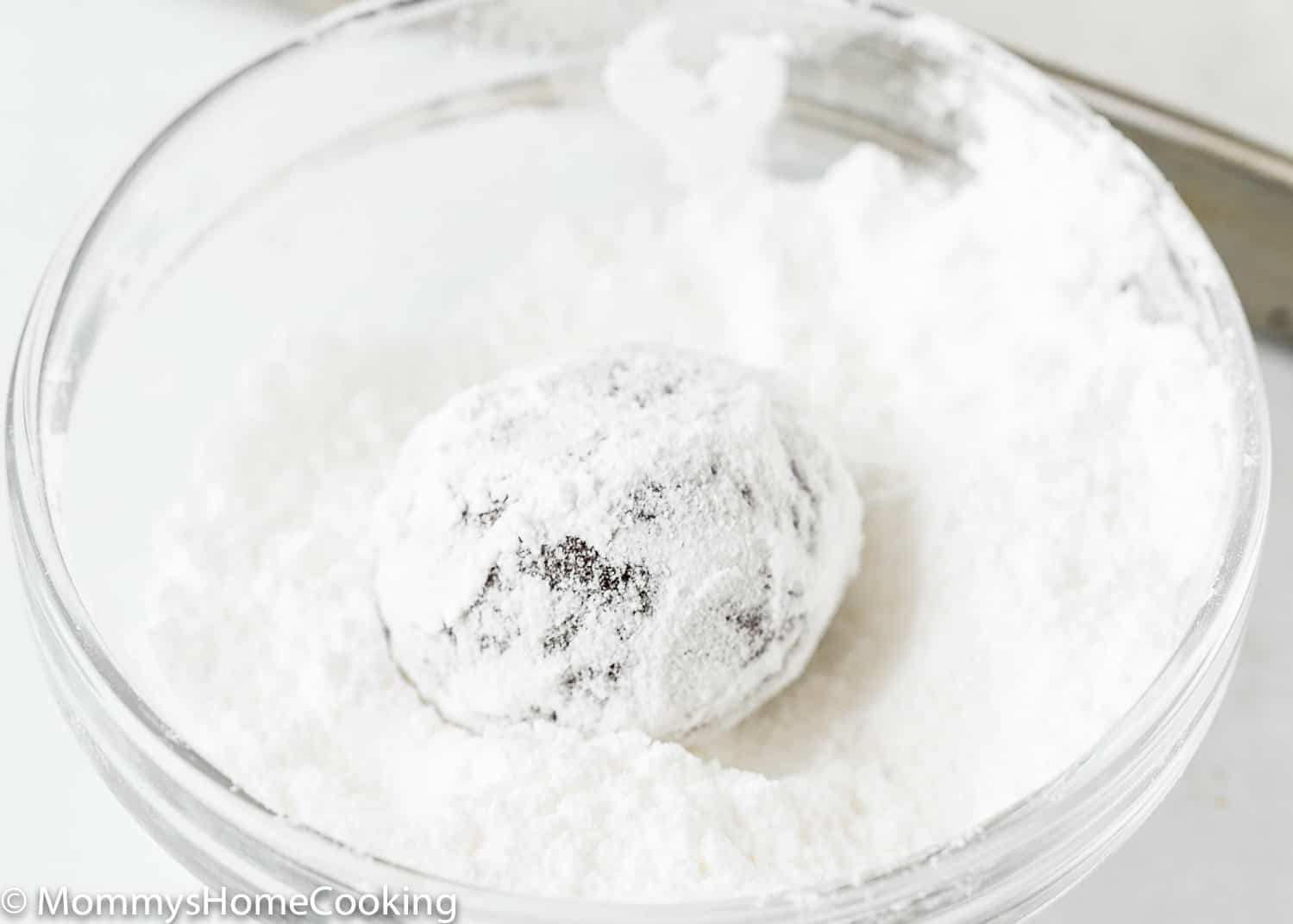 Eggless Chocolate Crinkle Cookie dough ball in a bowl with powdered sugar