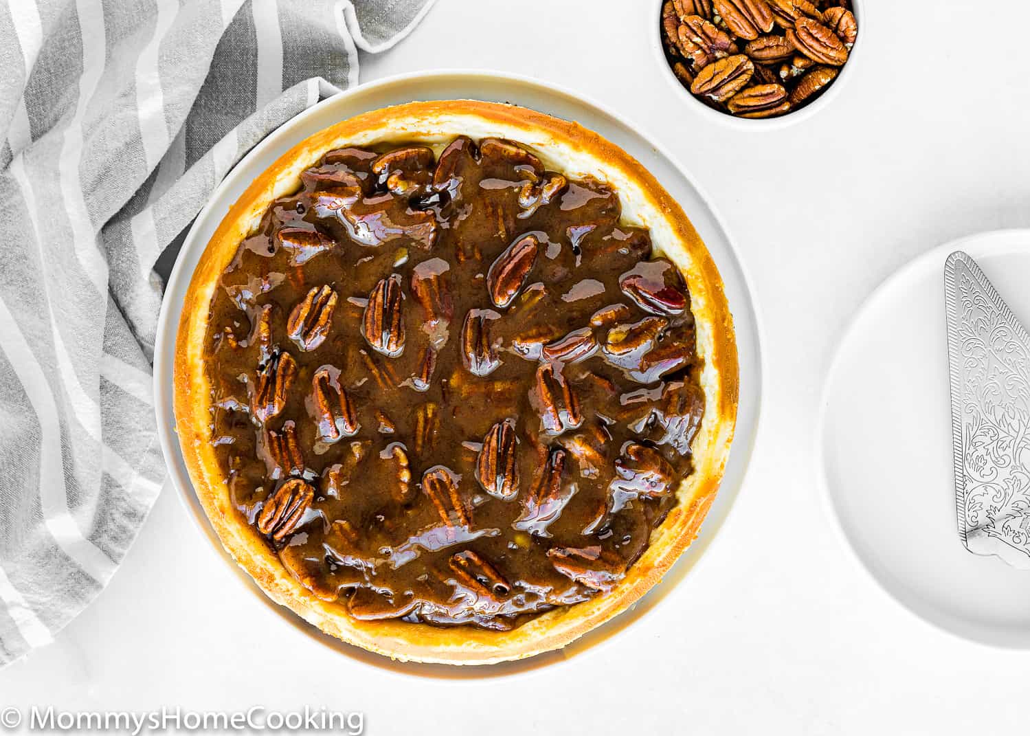 overhead view of a Eggless Pecan Pie Cheesecake over a table with a gray kitchen towel on the side