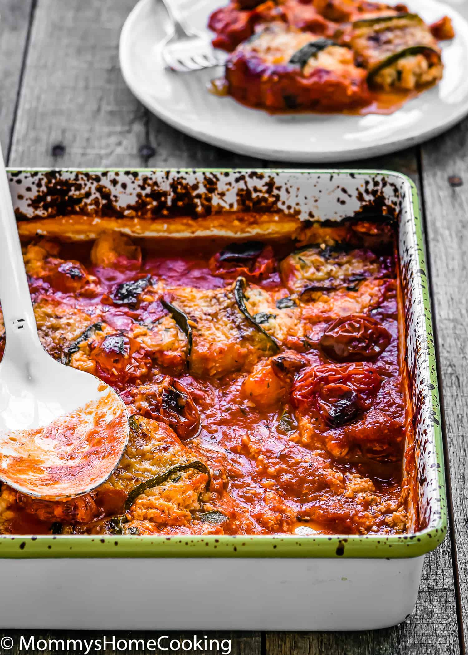 EGGLESS LASAGNA ZUCCHINI ROLLS in a baking dish with a spoon