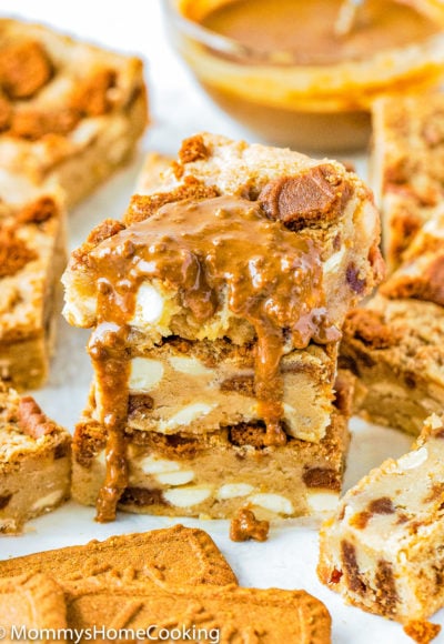 stack of three Eggless Biscoff White Chocolate Blondies drizzled with more biscoff sauce
