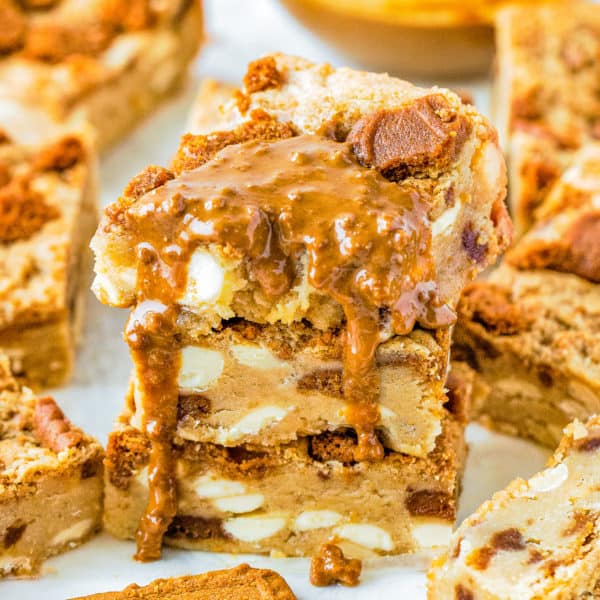 stack of three Eggless Biscoff White Chocolate Blondies drizzled with more biscoff sauce
