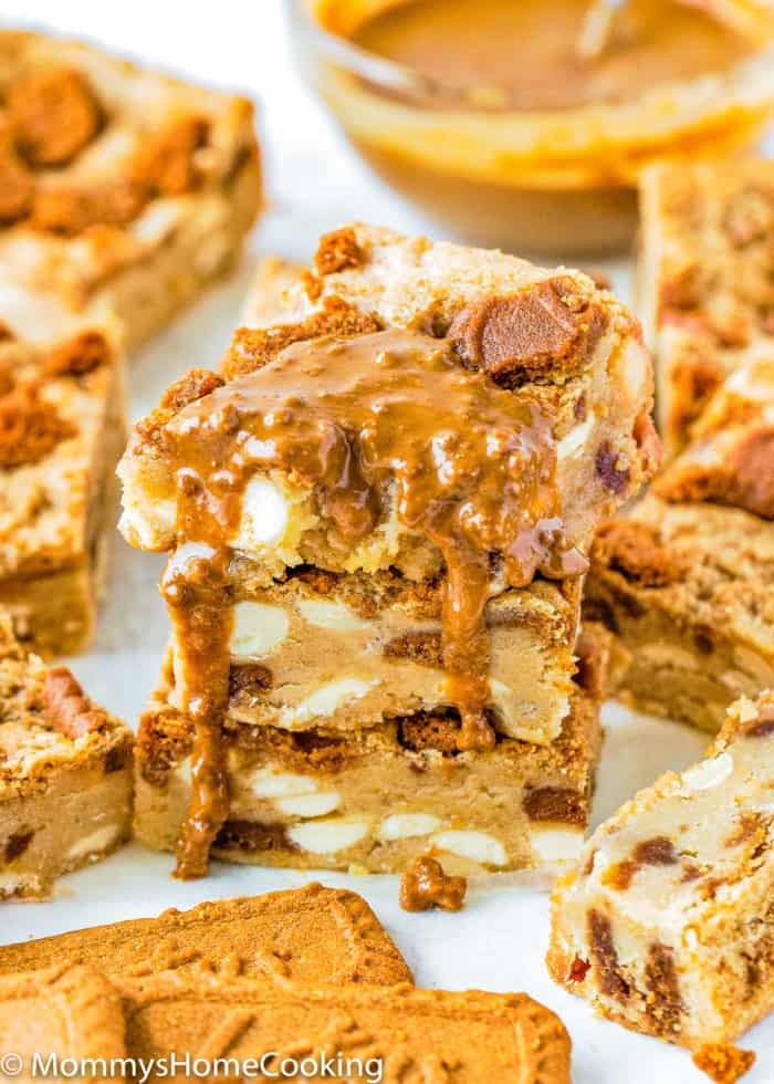 stack of three Eggless Biscoff White Chocolate Blondies drizzled with more biscoff sauce