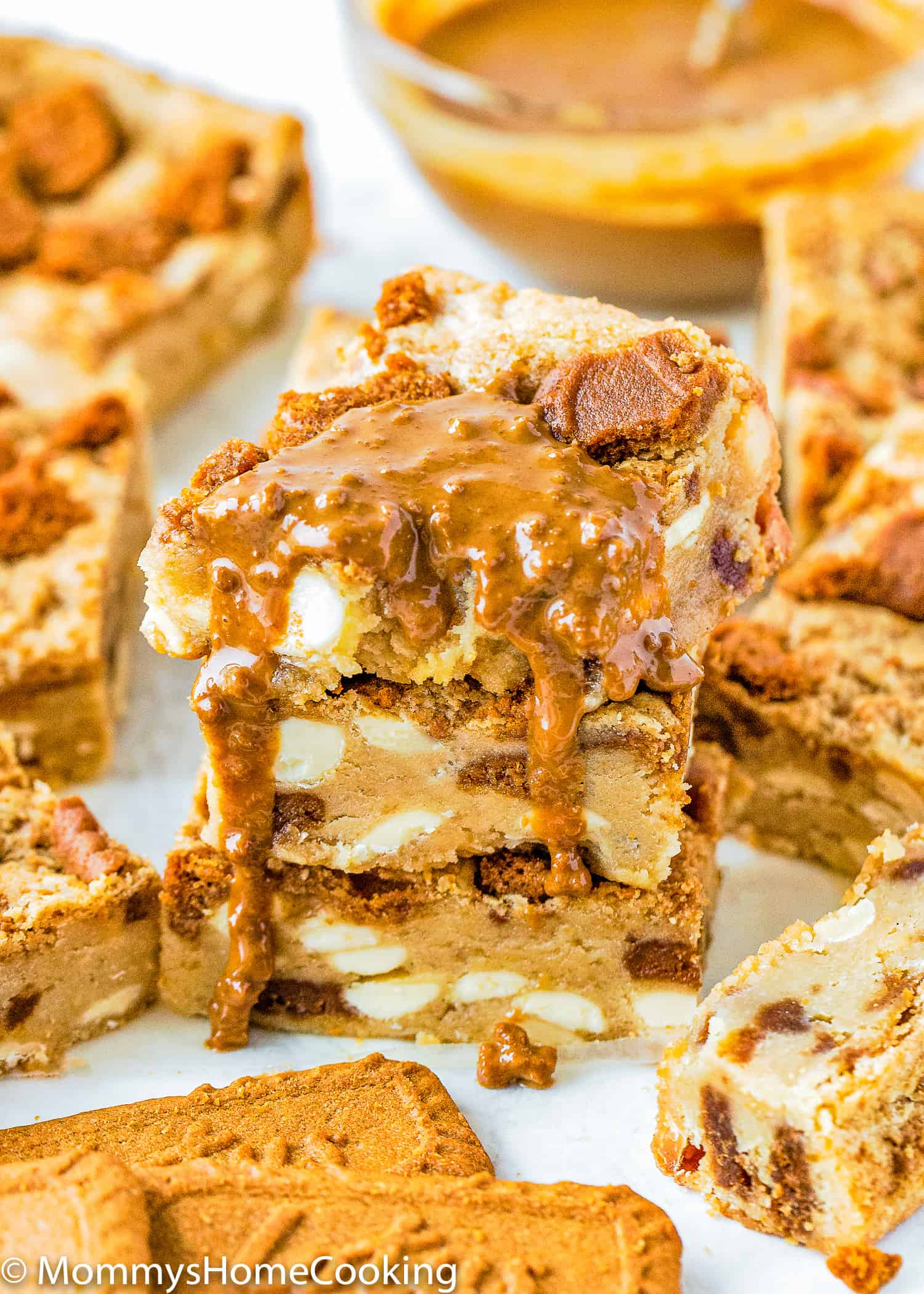 stack of three Eggless Biscoff White Chocolate Blondies drizzled with more biscoff sauce.