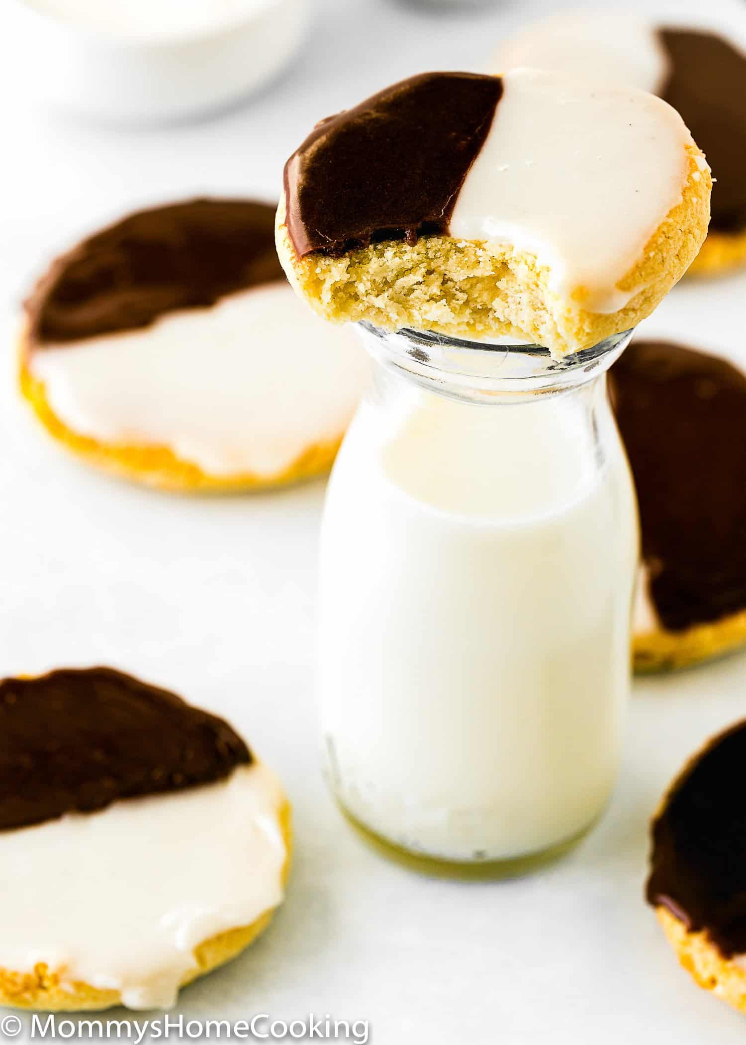 bitten Black and White Cookie in the top os a jar with milk