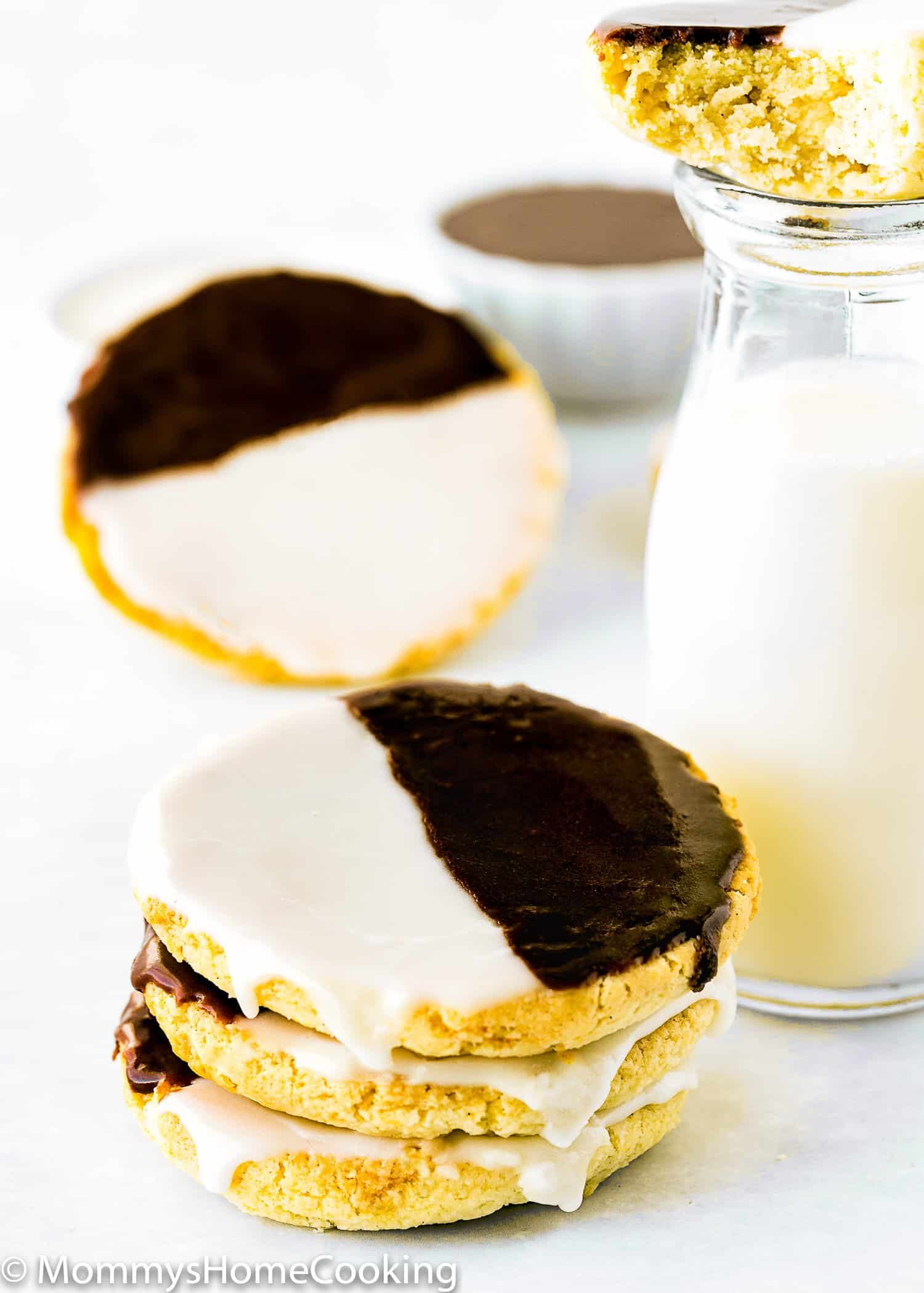 stack of three Eggless Black and White Cookies next to a glass of milk.