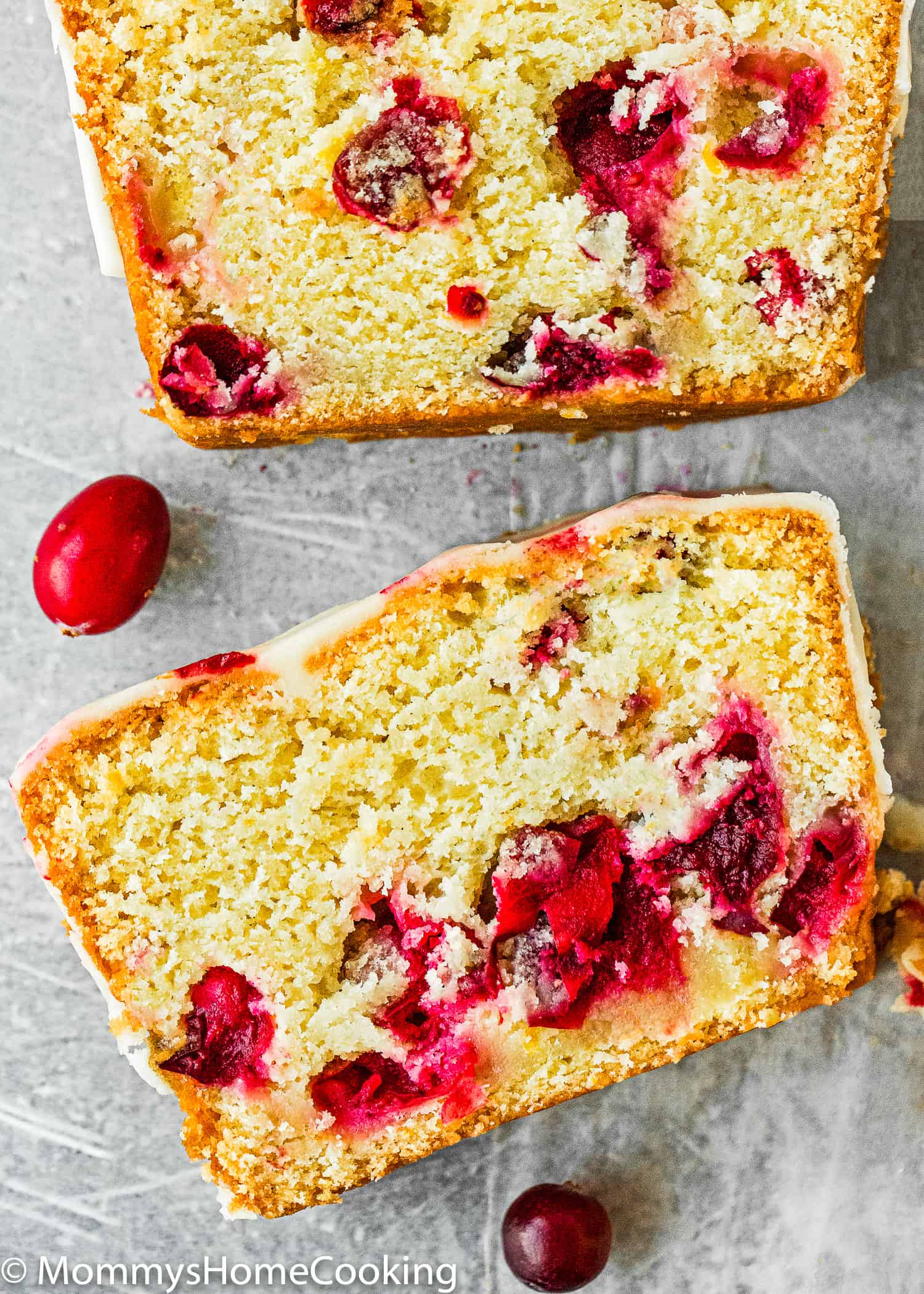 two slices of Eggless Cranberry Orange Bread over a gray surface