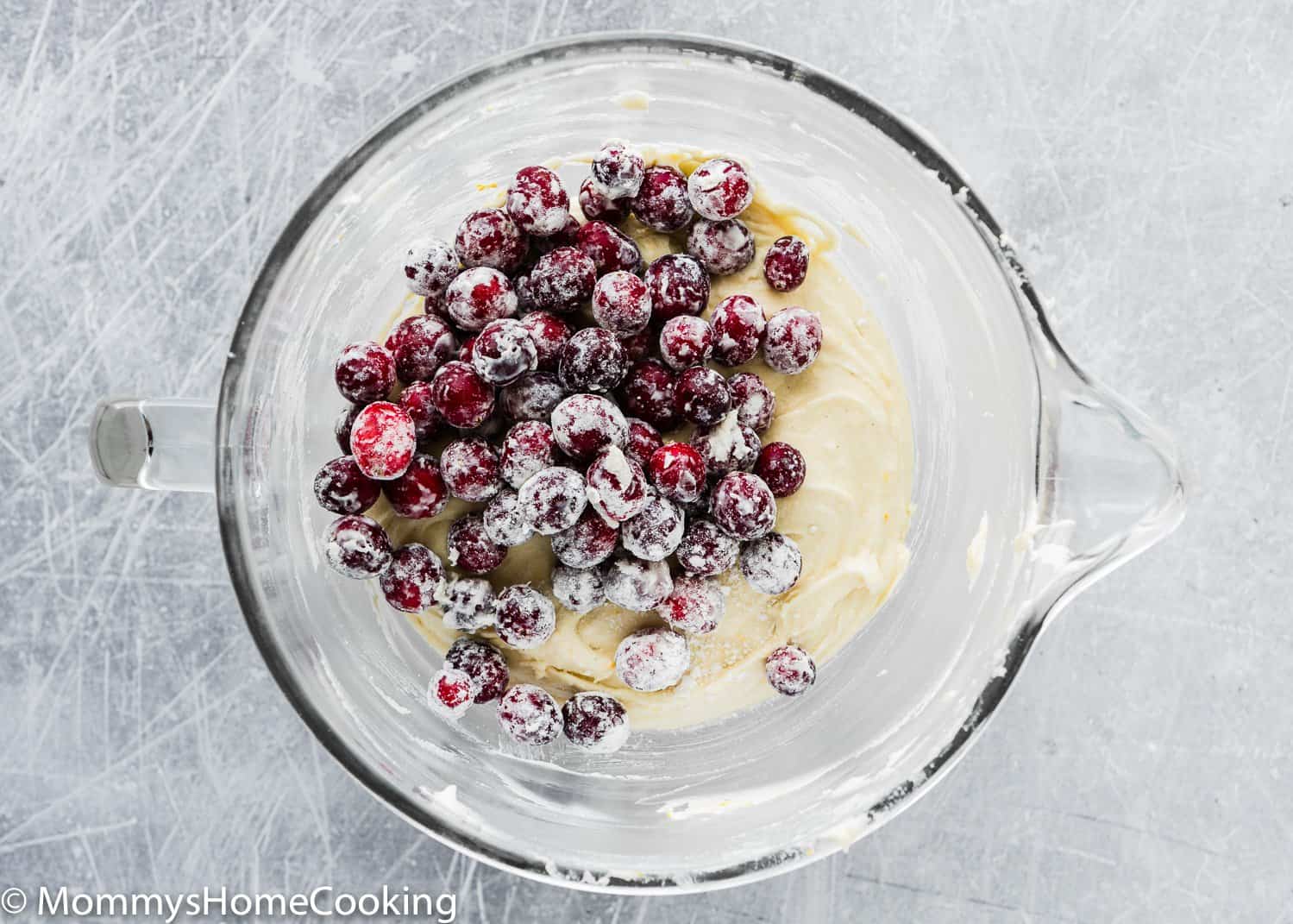 Eggless Cranberry Orange Bread batter with fresh cranberries on top in a stand mixer bowl. 