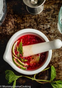 overhead view of a pestle with Lime juice, Sugar, Vodka, Fresh raspberries, Fresh mint leaves