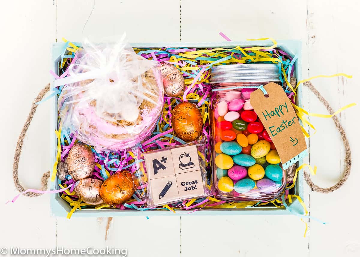 a eater basket with homemade cookie, chocolates, candies, and stamps inside.