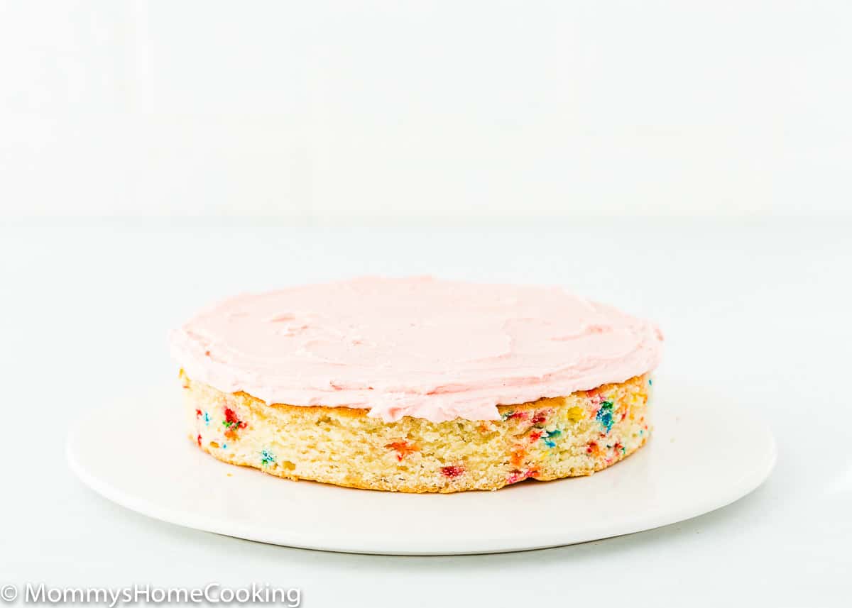 a cake layer of egg-free confetti cake with pink buttercream on top.