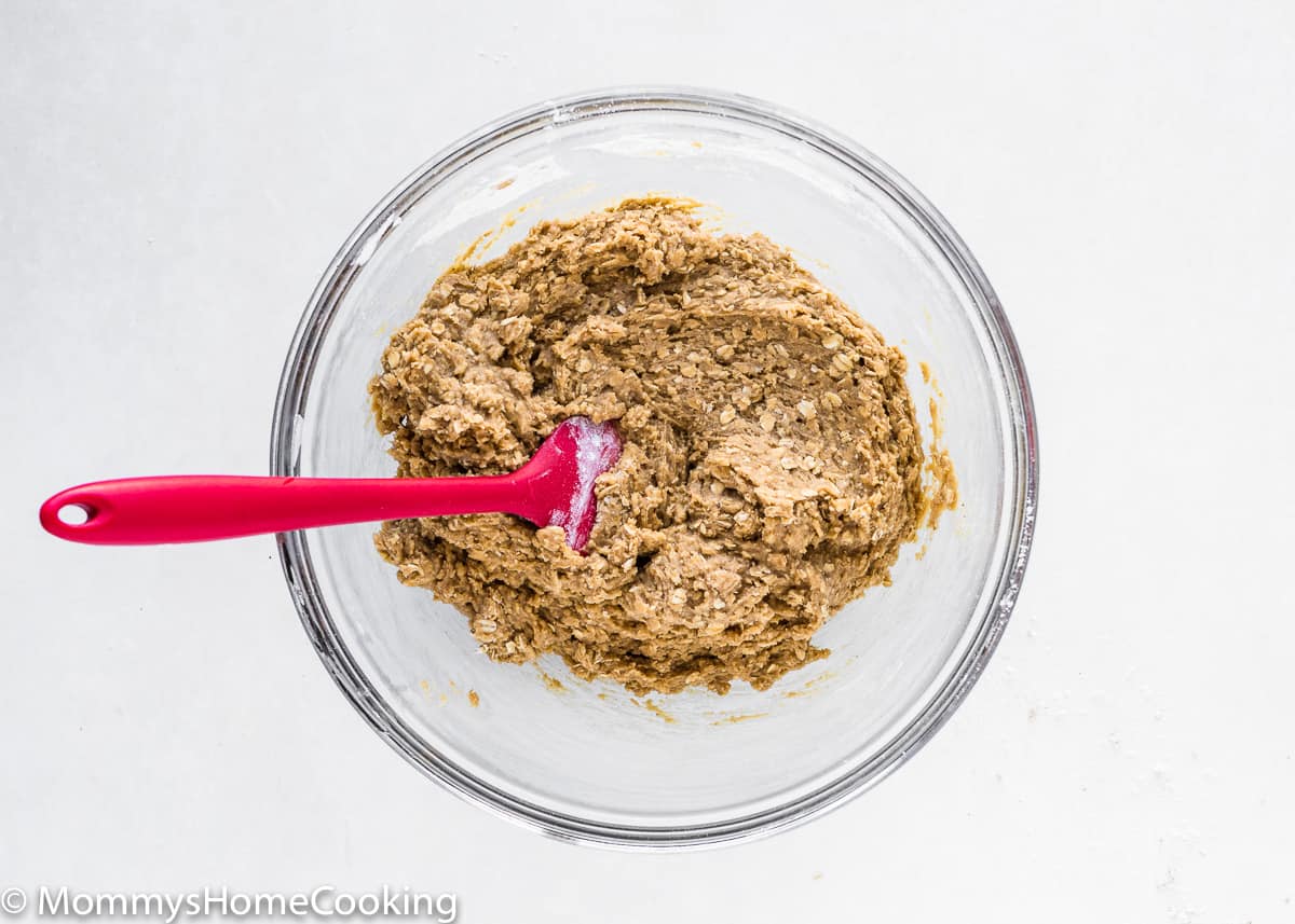 eggless oatmeal cookie dough in a mixing bowl with a red spatula.