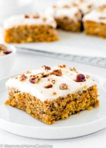 whole slice of Eggless Pineapple Carrot Sheet Cake on a white plate with the whole cake in the background.
