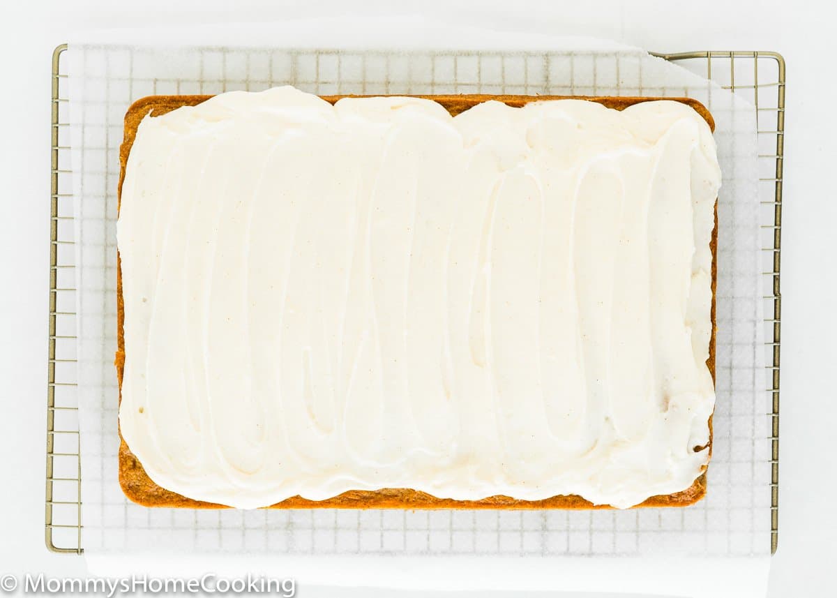 whole egg-free pineapple carrot cake with cream cheese frosting over a cooling rack.