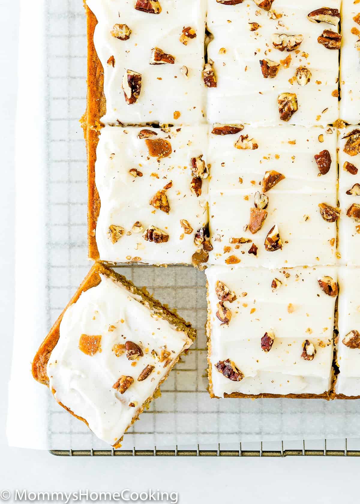 cut Eggless Pineapple Carrot Sheet Cake with frosting and nuts over a cooling rack.