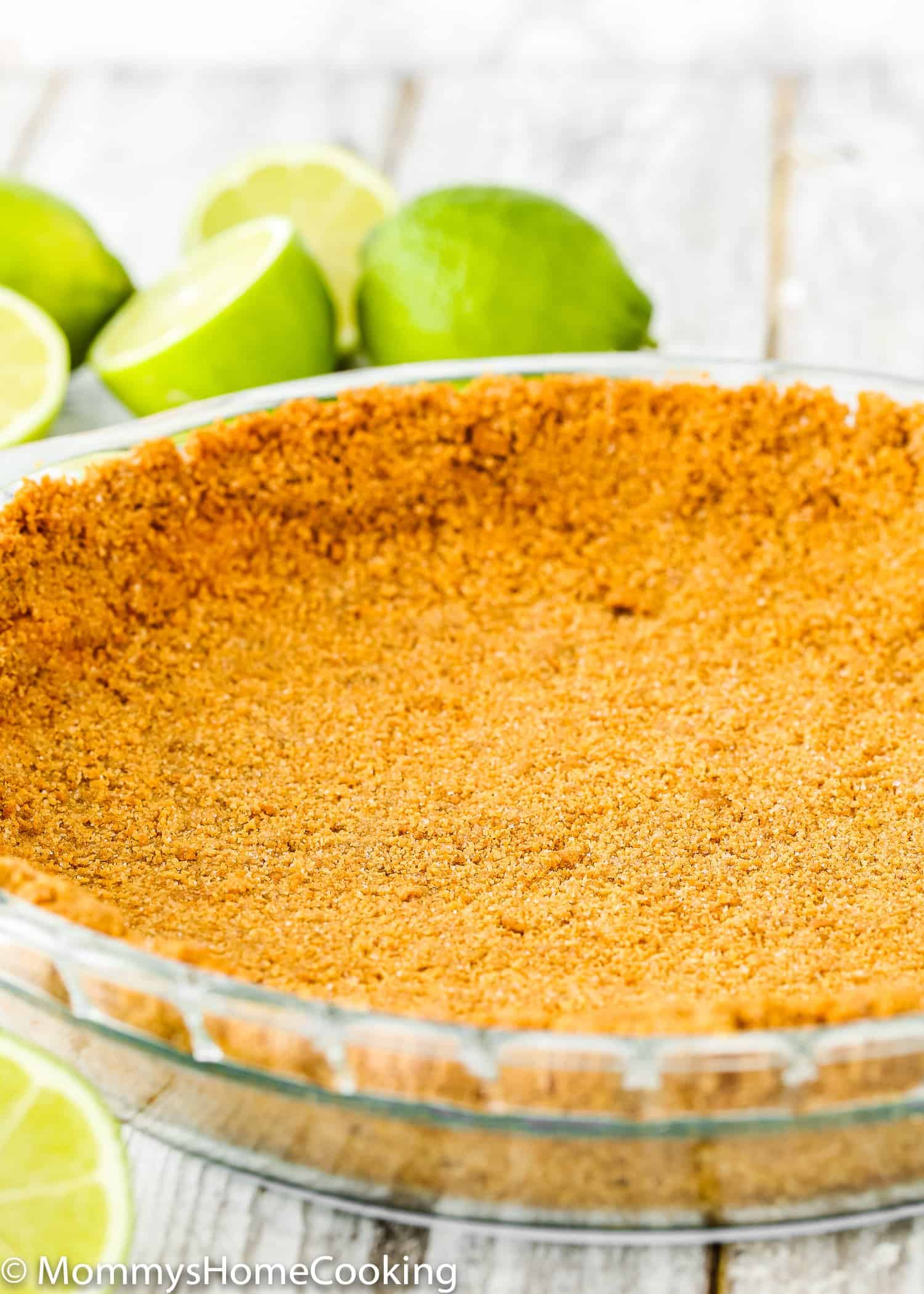 graham cracker crust in a pir dish with key lime on the background.