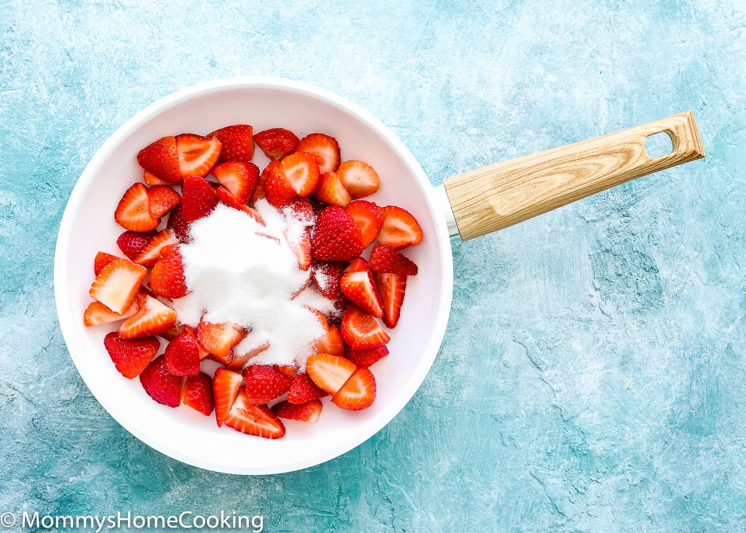 Strawberries and sugar in a white skillet.