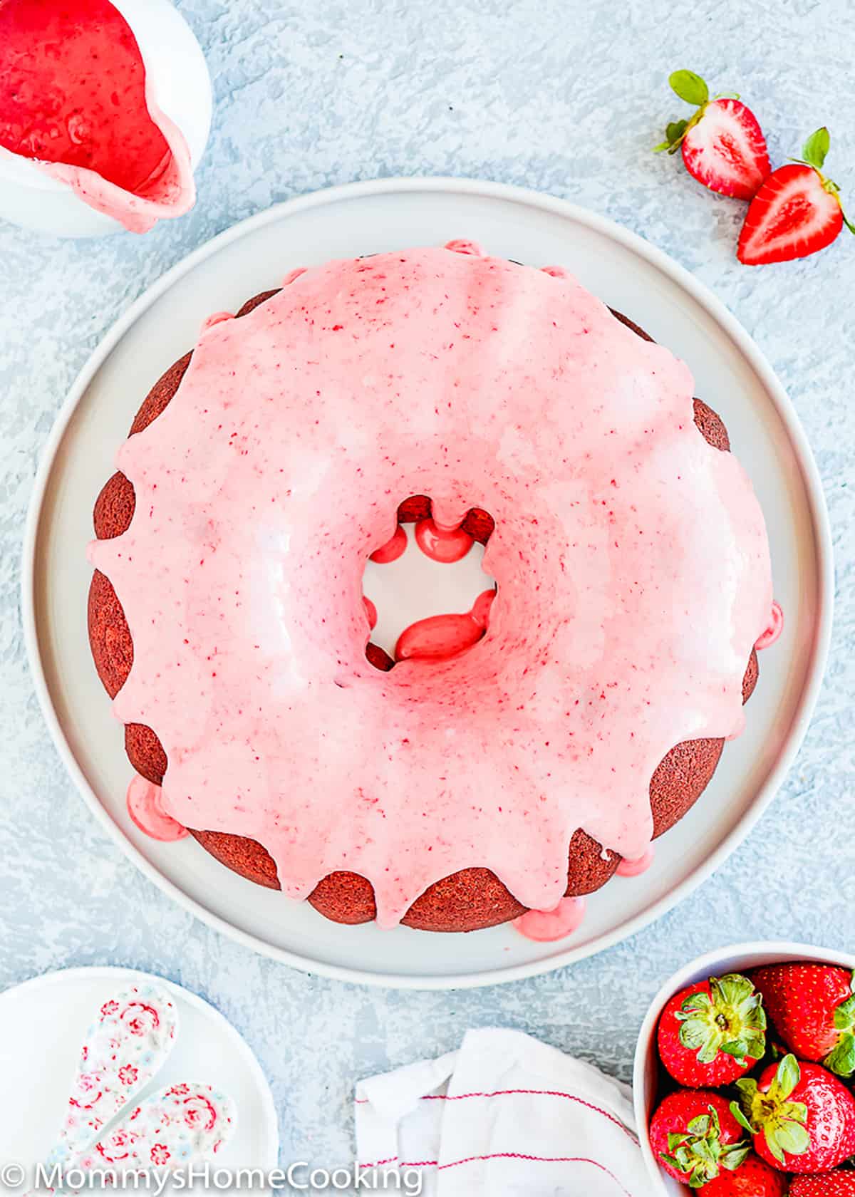 a whole egg-free homemade strawberry bund cake on a serving plate with glaze.