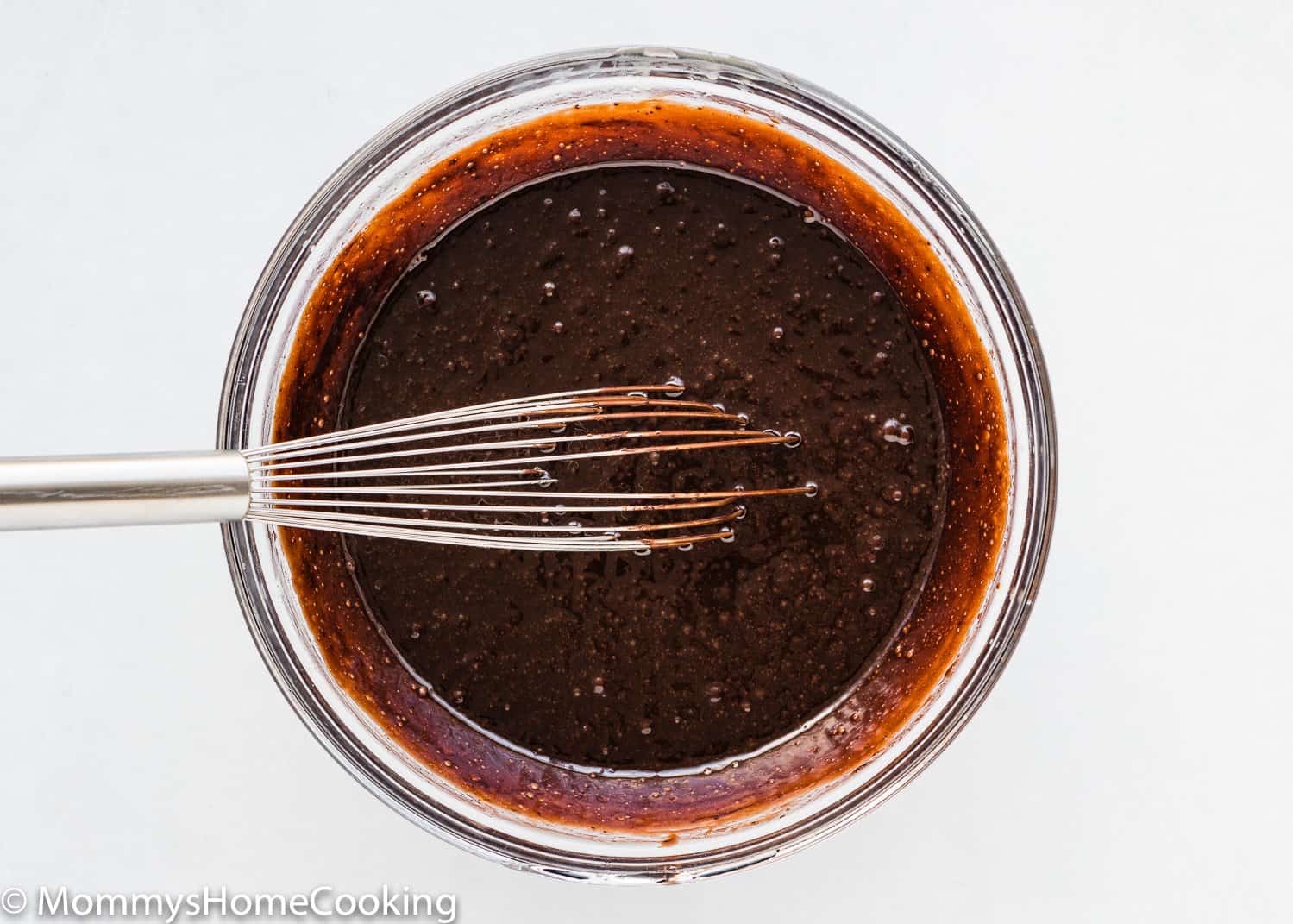 wet ingredients needed to make brownies without eggs in a bowl with a whisk.