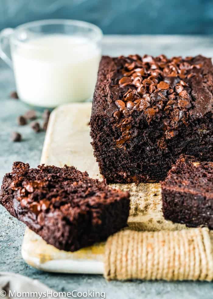 sliced Eggless Chocolate Banana Bread over a wooden board with a glass of milk in the background.