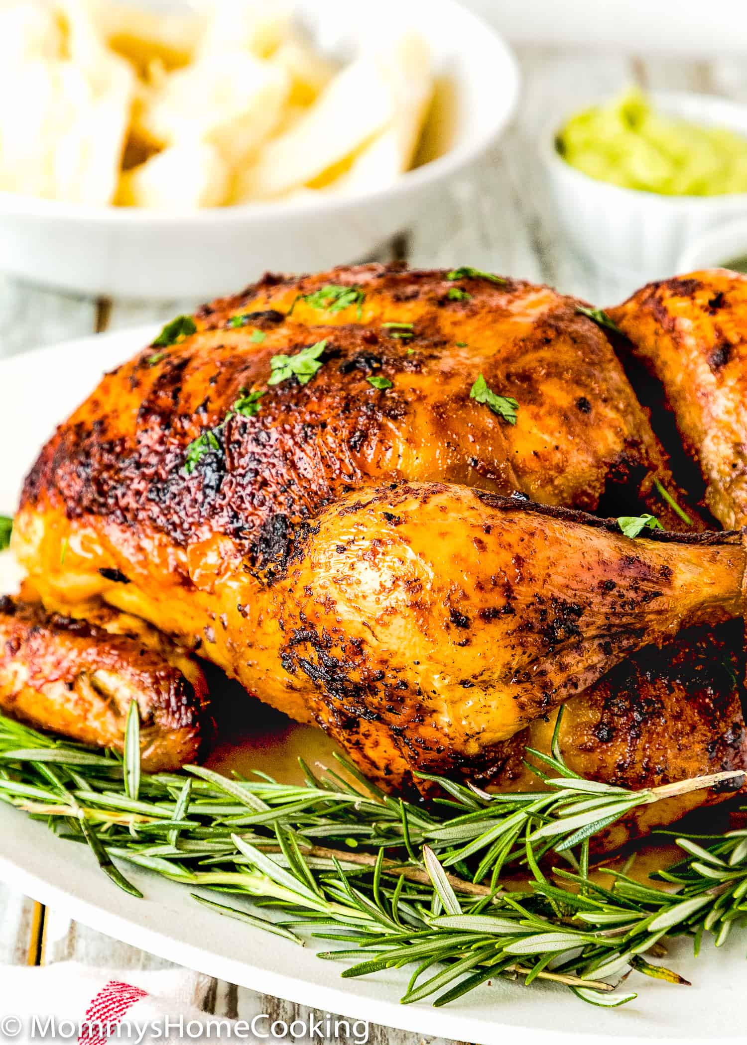 Venezuelan style roasted chicken over a plate with fresh rosemary.