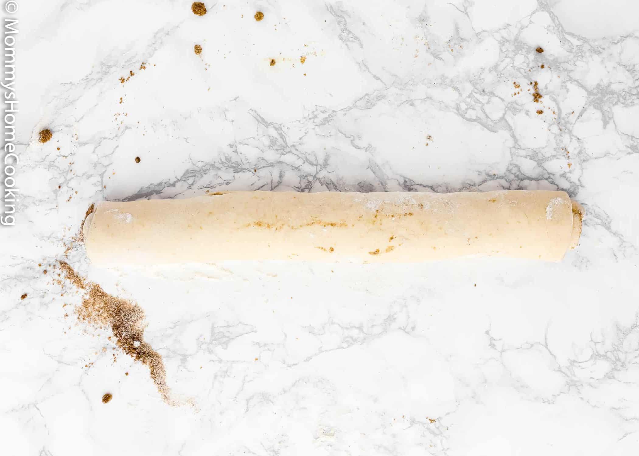 Egg-free cinnamon roll dough rolled out into a log.