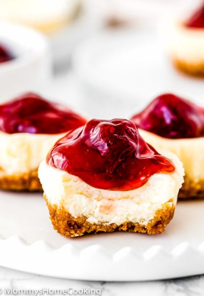 a bitten egg-free strawberry mini cheesecake on a plate showing its creamy texture..