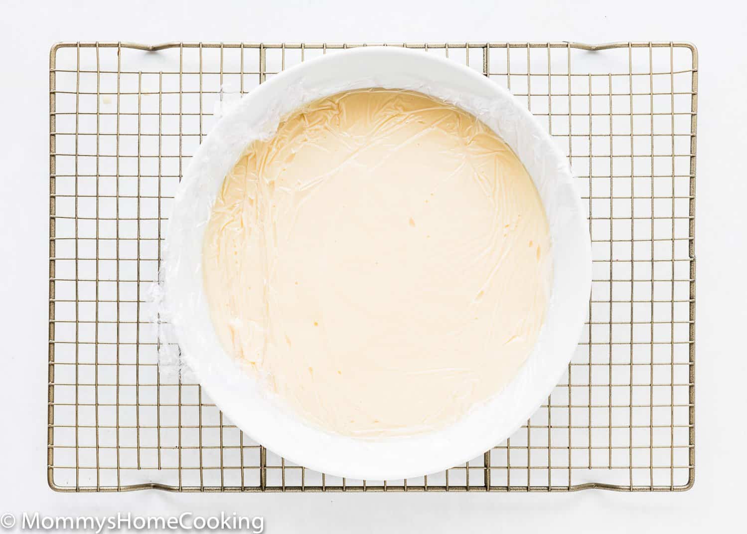 homemade egg-free vanilla pudding in a bowl covered with plastic wrap