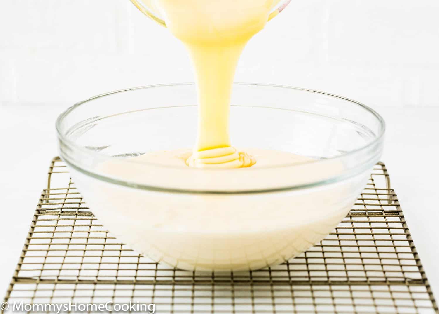 sweetened condensed milk being poured over egg-free homemade pudding.