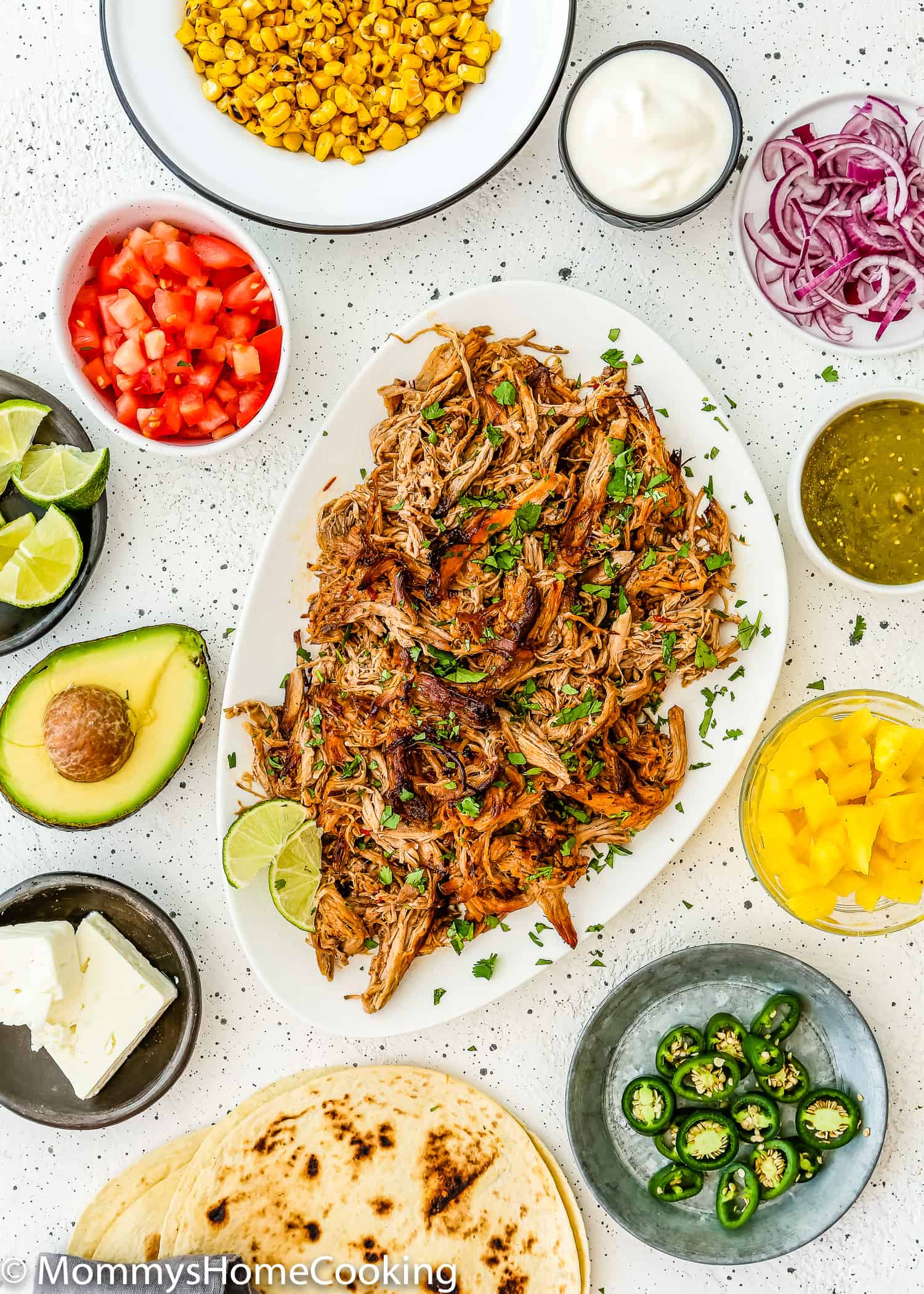 Slow Cooker Chipotle Carnitas with taco toppings on the side.