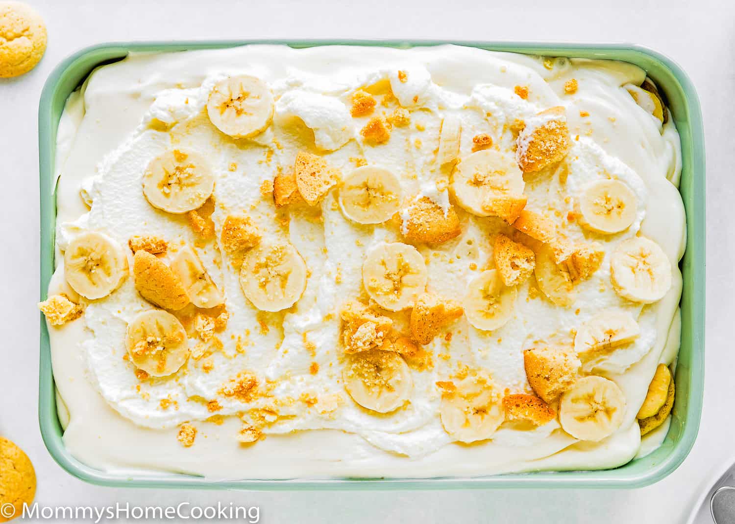 Homemade eggless banana pudding with whipped cream, crumbled wafers, and sliced bananas on top.
